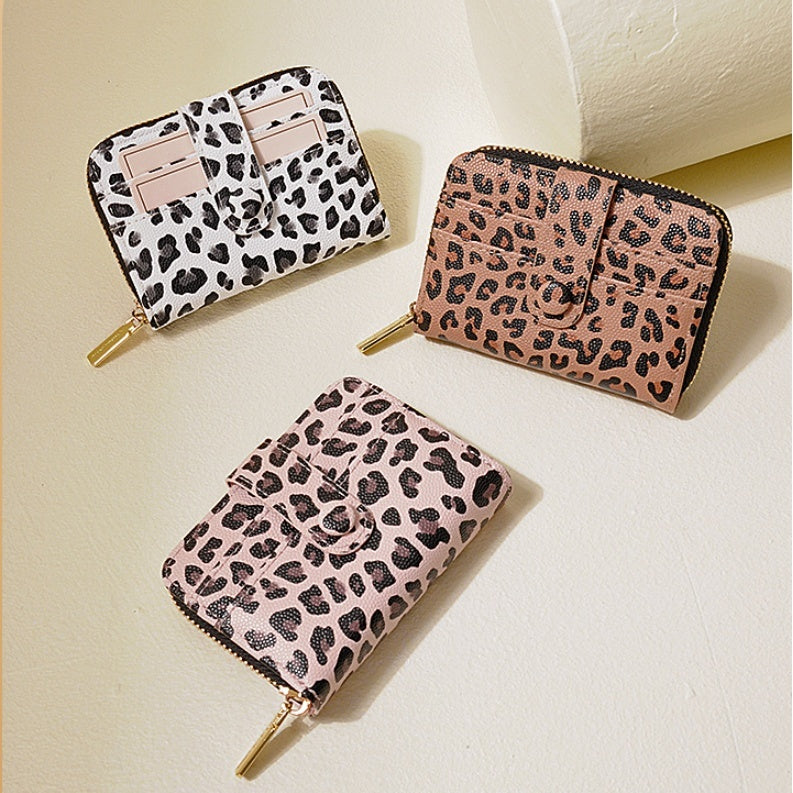 Set of three leopard print wallets in white, brown, and pink

Trendy women's compact wallet with leopard spots and zipper closure

Close-up of a white leopard print wallet with card slots

Fashionable brown leopard print bifold wallet for ladies

Pink leopard print mini wallet with gold zipper pull

